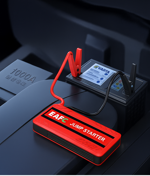 Red jump starter with clamps on a car battery